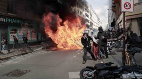 Демонстранти вървят със знаме до огнище за боклук по време на първомайско шествие в Париж, Франция, 1 май