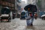 Жена държи чадър, докато върви по наводнена улица по време на проливен дъжд в Дака, Бангладеш, през юни.