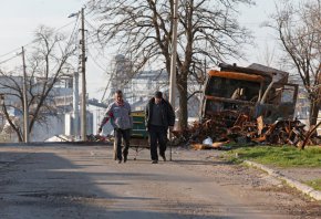 Местни жители минават покрай разрушен автомобил в южния пристанищен град Мариупол, Украйна, на 20 април. (Александър Ермоченко/Reuters)