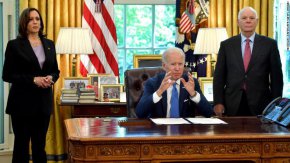 Вицепрезидентът на САЩ Камала Харис (вляво) и сенаторът на САЩ Бен Кардин (окръг Колумбия) (вдясно) слушат президента на САЩ Джо Байдън, който говори след подписването на Закона за отдаване под наем за отбрана на Украйна от 2022 г. в Овалния кабинет на Белия дом във Вашингтон, 9 май 2022 г.