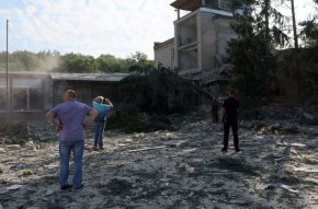 Хора стоят на мястото, където училище е разрушено при обстрел рано сутринта в Харков, в понеделник. (Лия Милис/Reuters)